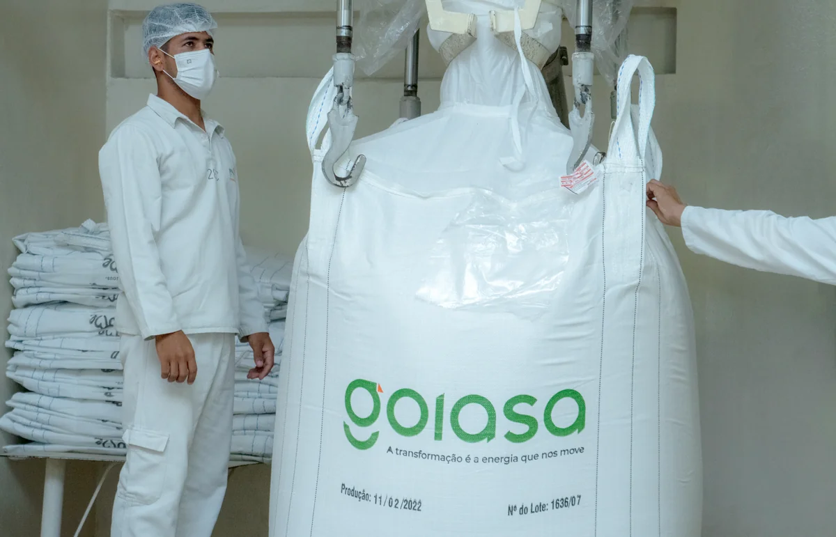 Trabalhador ao lado de uma embalagem de açúcar da Goiasa na área de produção.